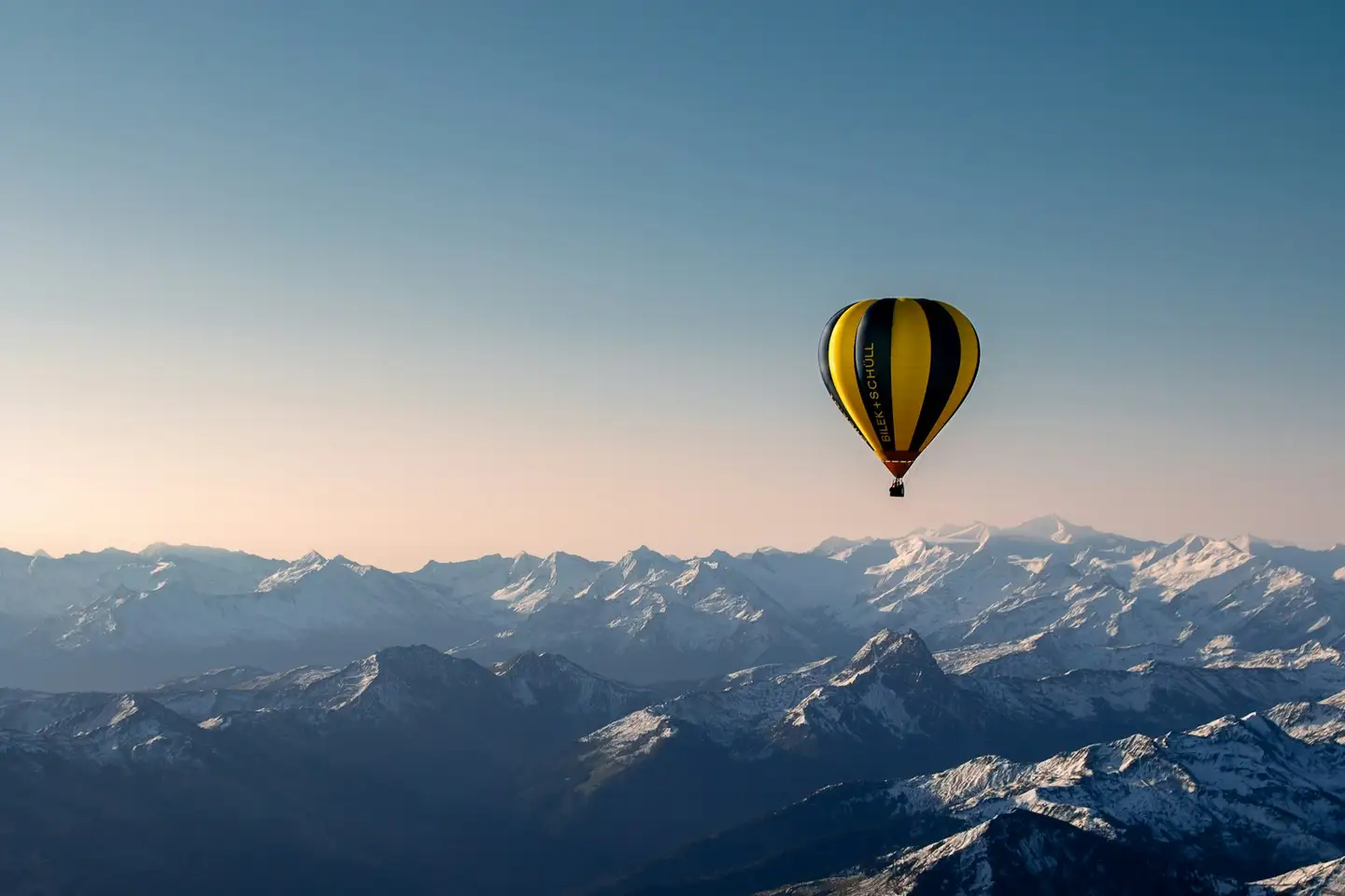 Luchtballon boven een berglandschap bij zonsopgang